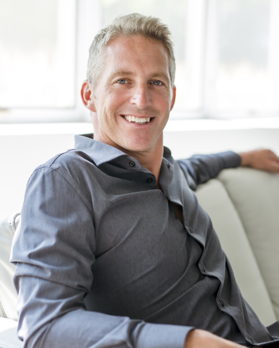 Photo of a smiling middle age man sitting on his couch